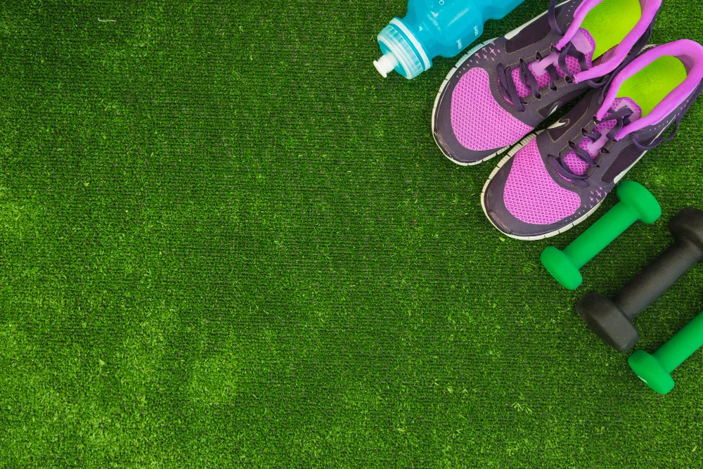 overhead-view-water-bottle-sport-shoes-dumbbells-green-turf